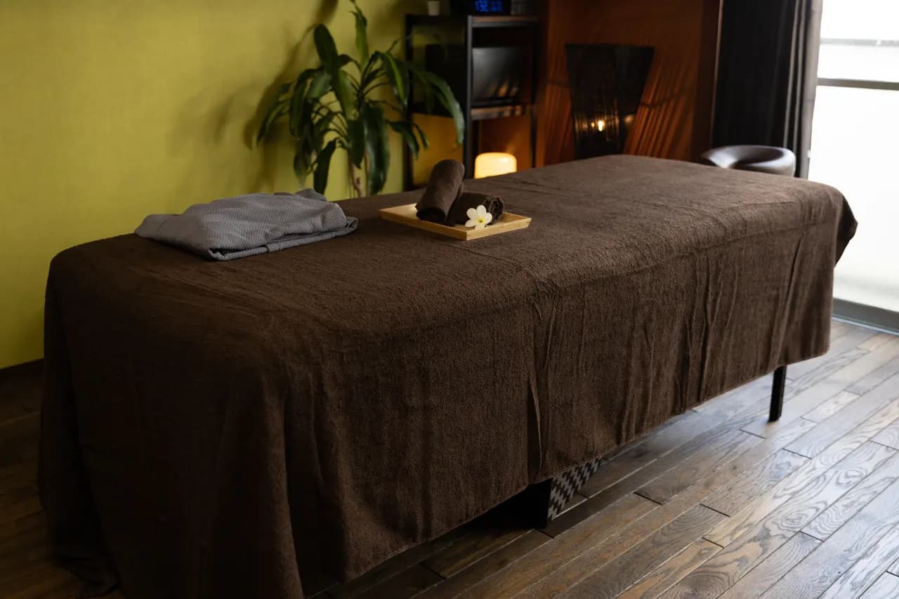 Kintsugi Spa の施術ベッド。タオルとプルメリアの花を置いた様子。